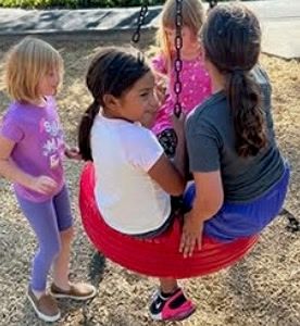 Four girls sharing a tire swing